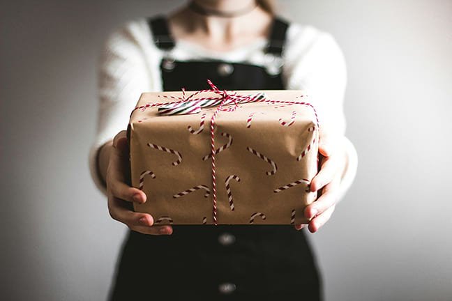 An image of a woman delivering a gift wrapped in candy canes